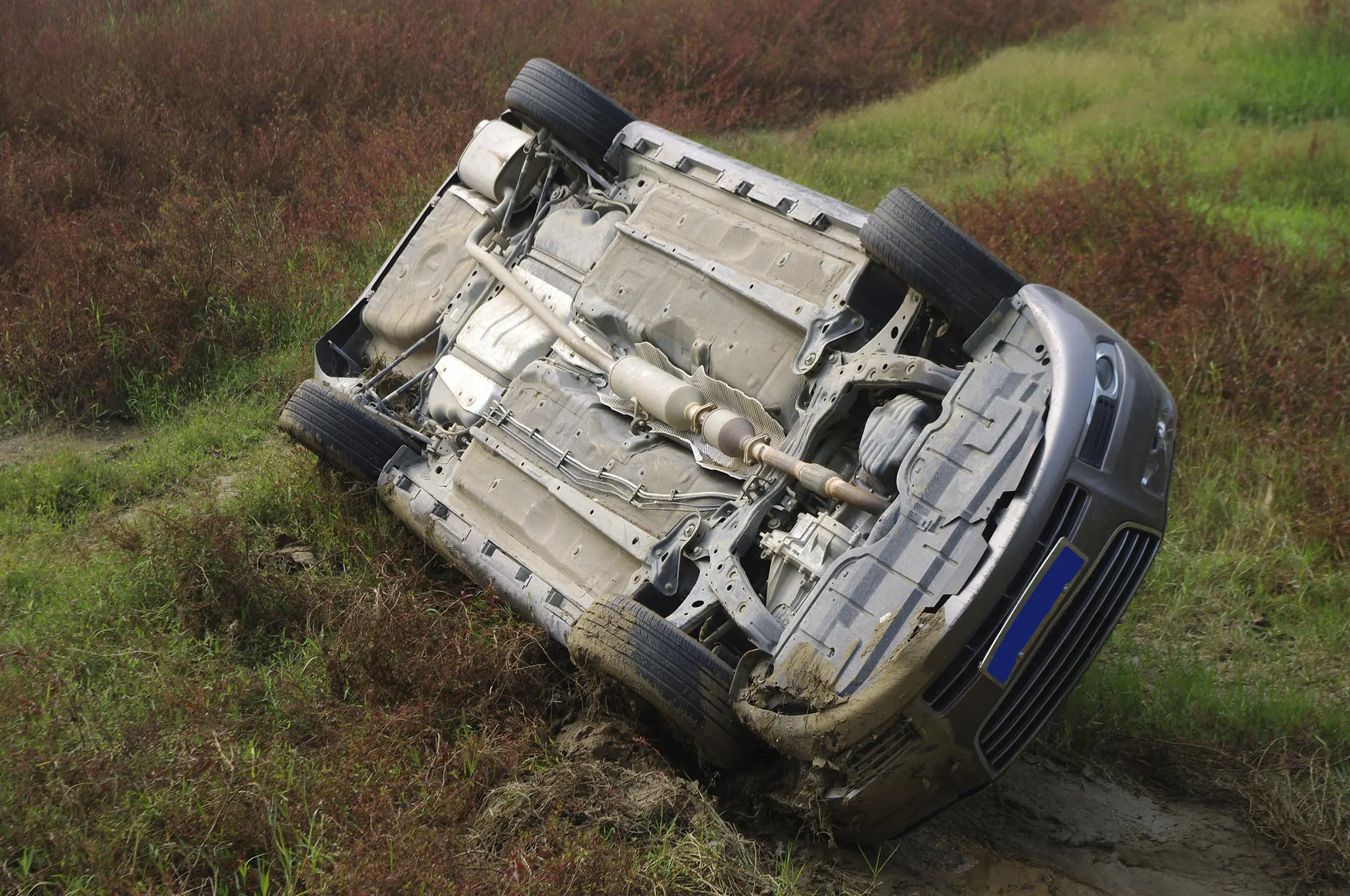 Rollover over accidents, like this blue car overturned in a ditch, can result in serious injuries - always call a qualified rollover accident lawyer if you have been injured in a rollover accident